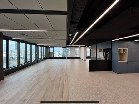 משרד להשכרה (משרד להשכרה) במגדל לוינשטיין, תל אביב, כולל חלונות גדולים עם נוף לעיר, ריצוף עץ בהיר ואריחים, ומטבחון עם ארונות כהים בצד ימין.