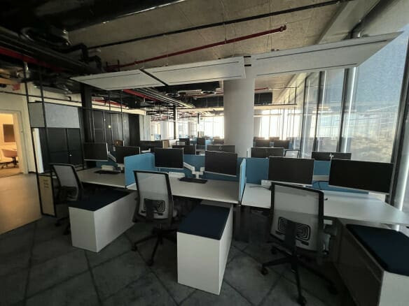 משרד מודרני בעל חלל פתוח להשכרת משרדים במגדל תוה"א, תל אביב, עם עמדות עבודה ריקות, כל אחת מהן מצוידת במסכים וכסאות, והכל מואר באור טבעי הנכנס מבעד לחלונות גדולים.