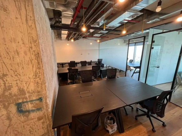 חלל משרדי מודרני המשתרע על פני 160 מטר במידטאון, עם שולחנות וכסאות שחורים, צינורות תקרה חשופים, נורות תלויות, קירות זכוכית וקיר בטון משמאל. החדר נראה ריק.