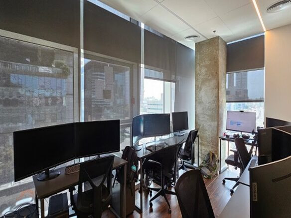 חלל משרדי מודרני עם מספר עמדות עבודה, מסכים גדולים, כיסאות ארגונומיים וחלונות מהרצפה לתקרה עם תריסים סגורים חלקית — אידיאלי עבור סאבליס להשכרה באזור המבוקש חסן ערפה.