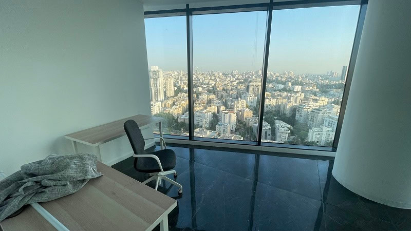 משרד להשכרה מודרני עם שני שולחנות וכסא, חלונות מהרצפה עד התקרה ונוף עירוני באור יום במגדל רסיטל.