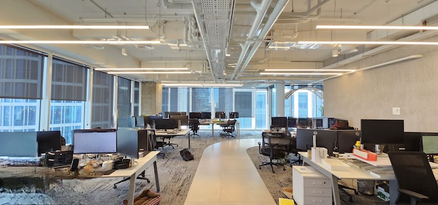 משרד מרוהט מודרני במתכונת פתוחה במגדל סקיי בתל אביב, הכולל שולחנות עבודה רבים, מסכי מחשב, כיסאות וחלונות גדולים הממלאים את חלל העבודה באור טבעי. השכרה זמינה לצרכי העסק שלכם.