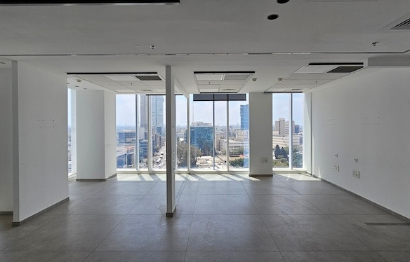 משרד להשכרה מודרני עם חלונות גדולים מהרצפה עד התקרה, קירות לבנים וריצוף אריחים, המשקיף על נוף עירוני תוסס ובניינים גבוהים במגדל סקיי.