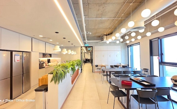 מטבח ומטבח מודרני מרוהטת להשכרה במגדל רסיטל, כולל תאורה תלויה, דלפק ארוך עם צמחים, מקררים ושולחנות שחורים עם כיסאות ליד חלונות גדולים.