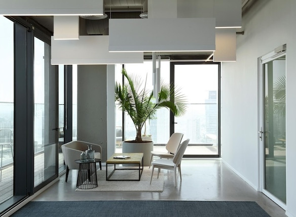 טרקלין משרדי מודרני עם חלונות גדולים, עציץ דקל, שלושה כיסאות ועיצוב מינימליסטי. אור טבעי ממלא את החלל, וניתן לראות מרפסת – אידיאלי עבור מי שמחפש משרד עם מרפסת או משרדים להשכרה שרונה במגדלי הארבעה.