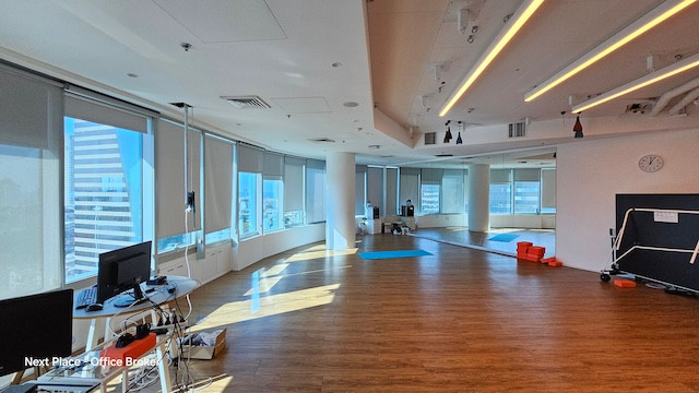 משרד מרוהט ומרווח עם רצפות עץ, מספר חלונות עם תריסים, שולחנות מחשב, ציוד משרדי ושעון קיר המציג את השעה 3:00. מושלם להשכרה במגדל סונול.