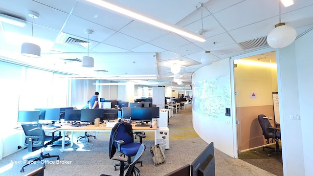 משרד מרוהט מודרני בעל חלל פתוח עם שולחנות עבודה, מסכי מחשב וכסאות; כמה אנשים עובדים בו ואור טבעי זורם פנימה מחלונות גדולים בצד שמאל. ממוקם במגדל סונול, אפשרות השכרה זמינה.