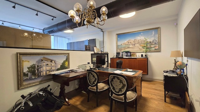 משרד מסורתי ברחוב מנחם בגין ליד מונטיפיורי בתל אביב, עם שני כיסאות מעוטרים, שולחן עץ עם מחשבים, יצירות אמנות ממוסגרות המעטרות את הקירות ונברשת התלויה מהתקרה.