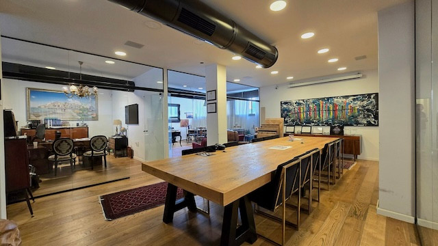 חלל משרדי מודרני להשכרת קומה בשכונת מונטיפיורי, הכולל שולחן ישיבות עץ ארוך, כיסאות שחורים, מחיצות זכוכית, רצפות עץ מלא וציורים צבעוניים על הקירות.