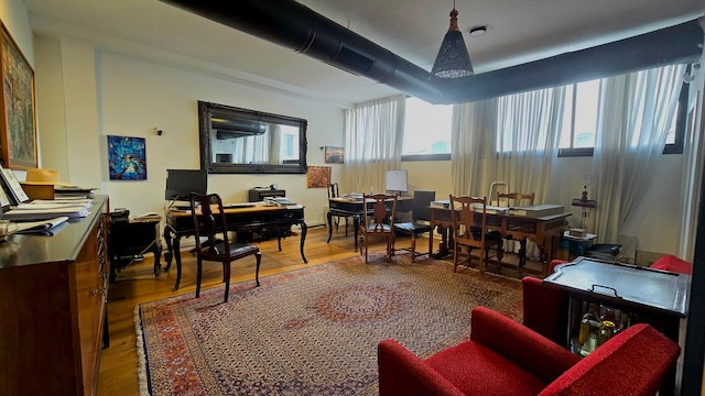 משרד מרווח בתל אביב עם ריהוט מעץ, שטיח גדול, מספר שולחנות וכסאות, מחשבים וחלונות גדולים עם וילונות המאפשרים כניסת אור טבעי – אידיאלי להשכרת משרדים ליד מנחם בגין.