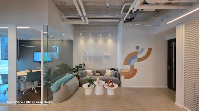 טרקלין משרדי מודרני במגדל סקיי עם כיסאות אפורים וכחולים, שולחנות עגולים לבנים, חדר ישיבות עם קירות זכוכית, אמנות קיר מופשטת וצינורות תקרה חשופים; כולל גישה למרפסת להפסקה באוויר הצח.