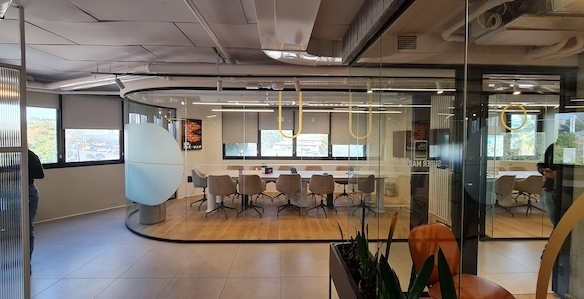 משרד מרוהט ומודרני עם חדר ישיבות בעל קירות זכוכית, שולחן ארוך, כיסאות, חלונות גדולים וצמחים דקורטיביים, הממוקם ברחוב דרך השלום בתל אביב. כולל גישה למרפסת גג מרווחת בגודל 600 מ"ר.