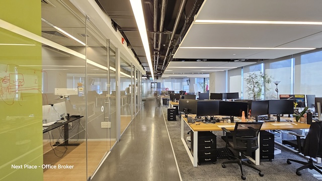 משרד מודרני בעל חלל פתוח בבית קרדן, תל אביב, עם שורות של שולחנות, מחשבים וכסאות לצד חדר ישיבות עם קירות זכוכית וחלונות גדולים המאפשרים כניסת אור טבעי — משרד להשכרה אידיאלי.