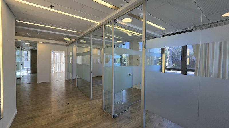 משרד מודרני במתחם הבורסה עם חדרי ישיבות בעלי קירות זכוכית, פסי פרטיות חלבית, ריצוף עץ, חלונות גדולים המאפשרים כניסת אור טבעי וגישה למרפסת ענקית.