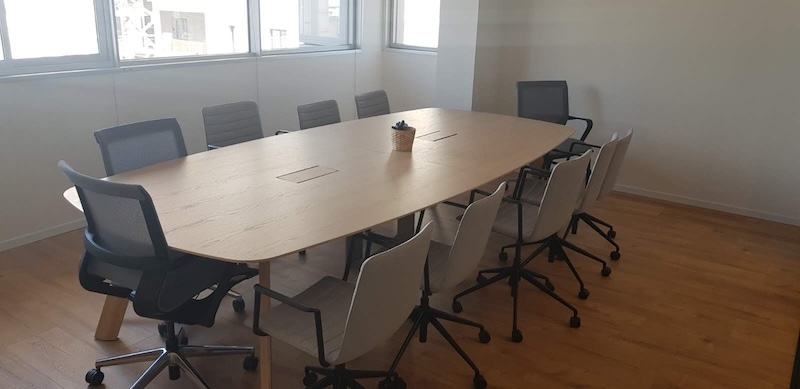 חדר ישיבות מודרני במשרד להשכרה, הכולל שולחן עץ, שמונה כיסאות משרדיים, מחזיק עטים וחלונות גדולים הממלאים את החלל באור טבעי. ממוקם ליד יגאל אלון תל אביב, לסביבת עבודה מושלמת.